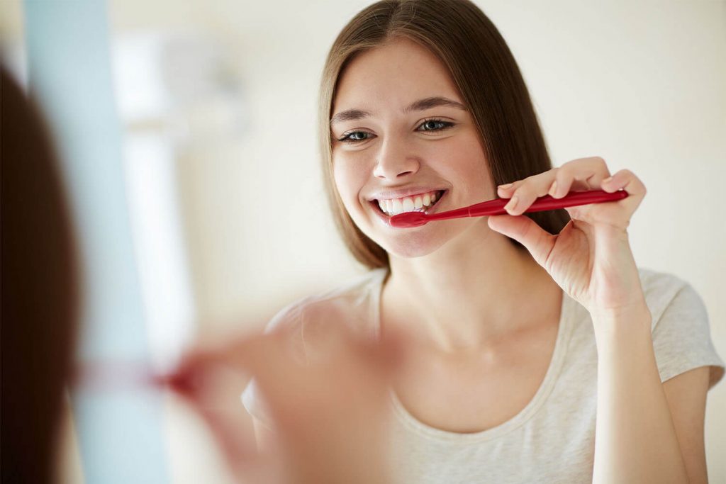 A smiling woman brushing her teeth